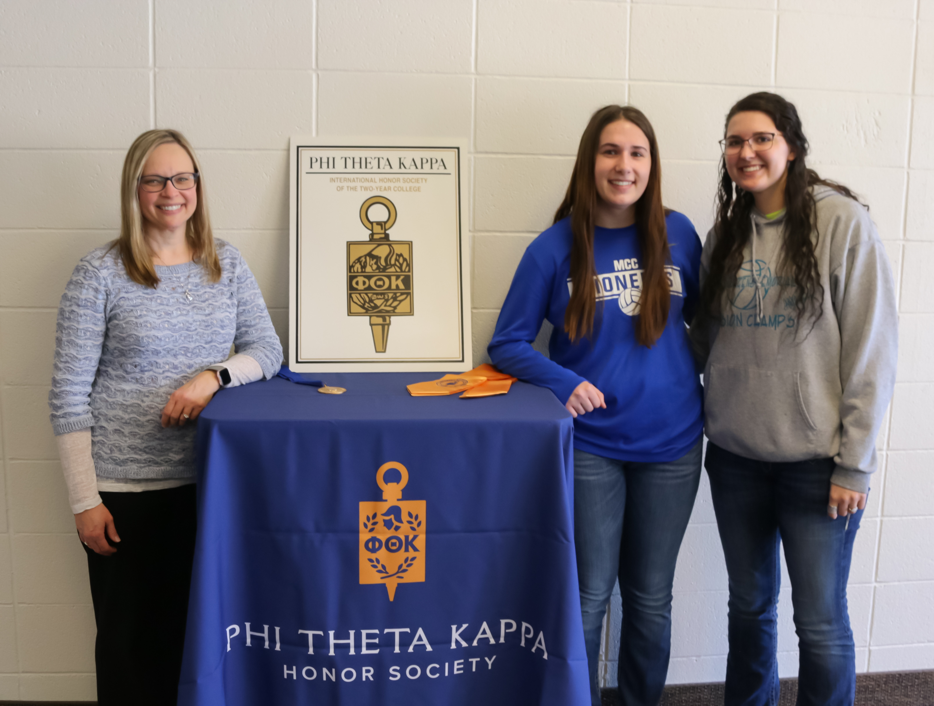 Image of three females standing by table