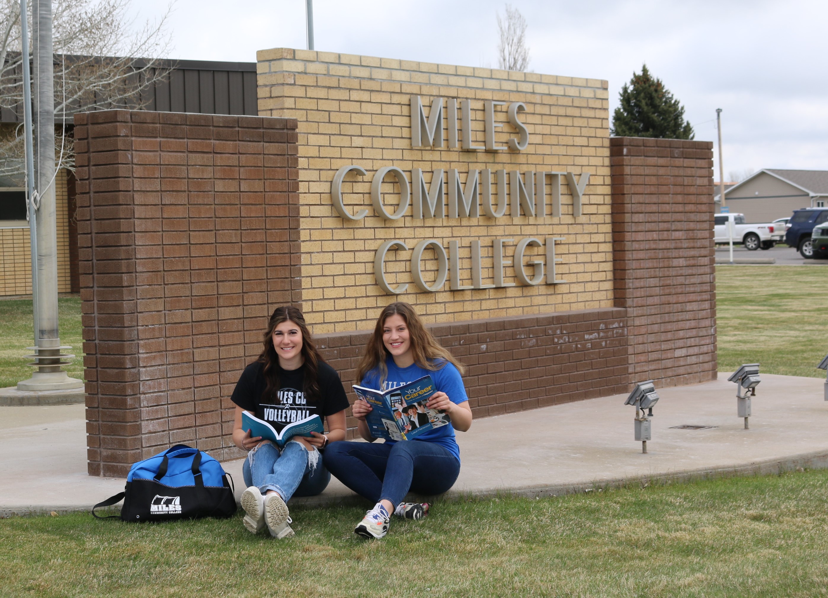 Image of two female students studying on campus lawn